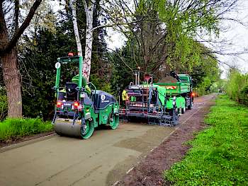 Maschinen für den Wegebau:  Ein Fertiger beim Einbau der Deckschicht für eine Wassergebundene Wegedecke. Anschließende Verdichtung durch die Tandem-Walze.