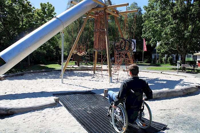 Rollstuhlfahrer auf einer Inklusions-Matte auf Spielplatz