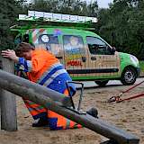 Spielplatzprüferin an Wippe. Im Hintergrund Spielplatzkrontrollfahrzeug