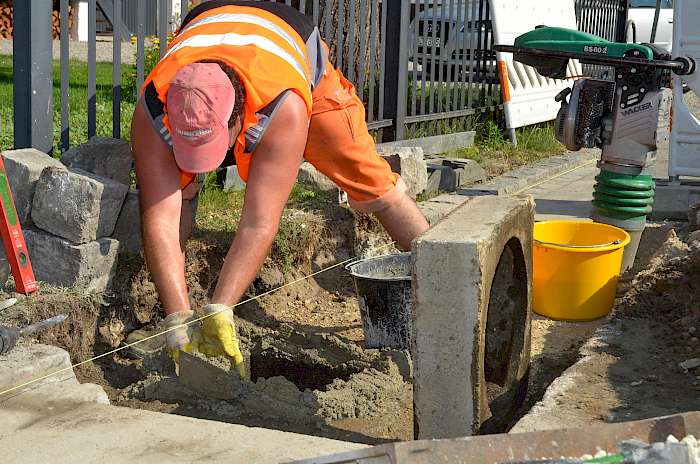 Bauhofmitarebiter bei Straßensanierungsarbeiten im Hochsommer